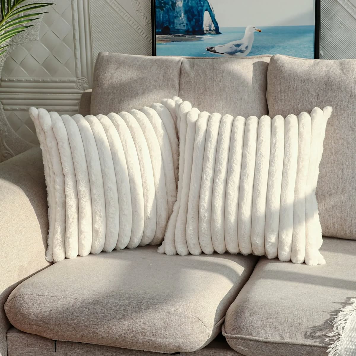 Deux housses de coussin blanches en fausse fourrure sur un canapé